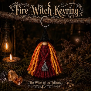 May include: A handcrafted yarn keyring featuring a witch figure with a black crocheted hat, long yellow and red hair, and a dark red dress. A small silver-toned flame charm is attached to the front. The text Fire Witch Keyring and The Witch of the Willows is visible.