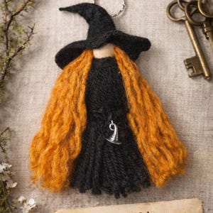 May include: A handmade doll named "Willow the Welcomer" with a black witch hat and dress, and orange hair. The doll has a silver charm and a metal keyring. The doll is made from wool felt and wood.