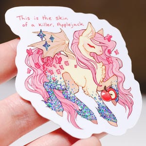 May include: A sticker featuring a cartoon pony with pink hair and wings, adorned with butterflies and glitter. The pony holds an apple and the text reads, "This is the skin of a Killer, Applejack."