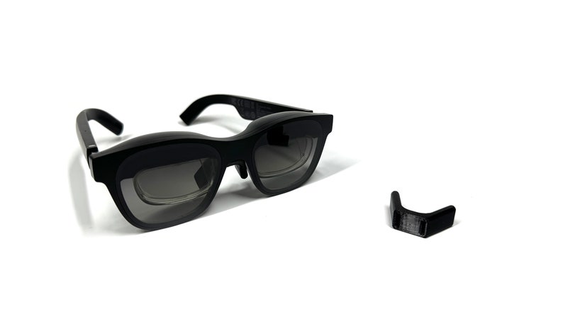 May include: Black framed glasses with a dark gray lens and a small black piece on the side.