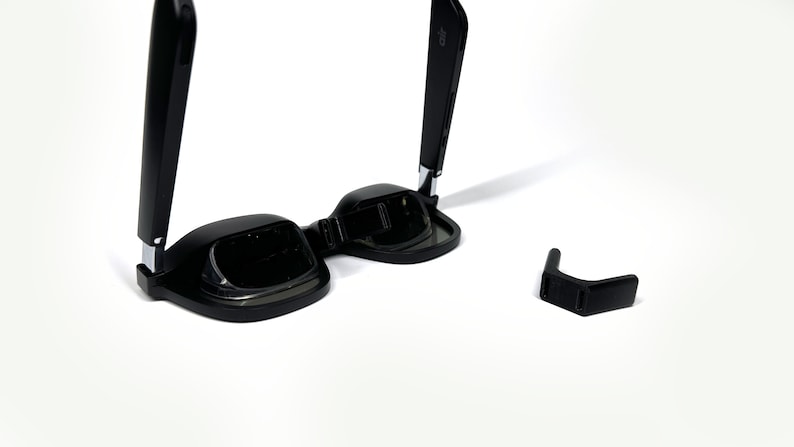 May include: Black foldable sunglasses with a silver hinge and a separate black nose piece.