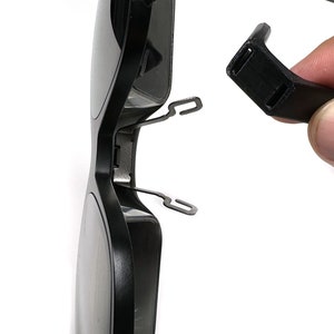 May include: A pair of black sunglasses with a broken arm. The arm is detached from the frame and is held in a hand.