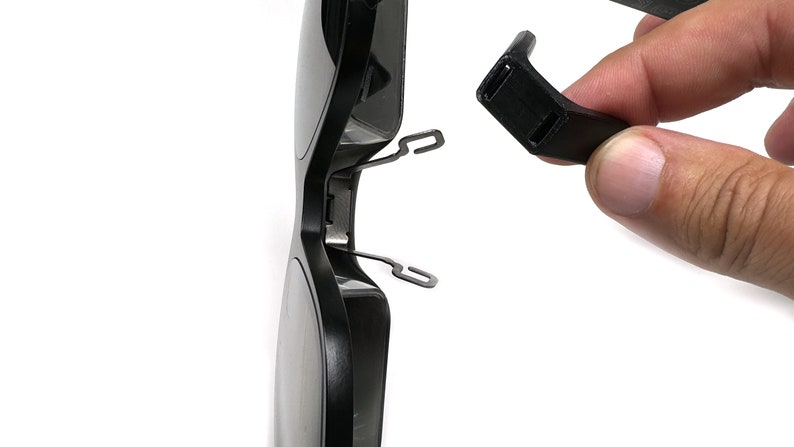 May include: A pair of black sunglasses with a broken arm. The arm is detached from the frame and is held in a hand.