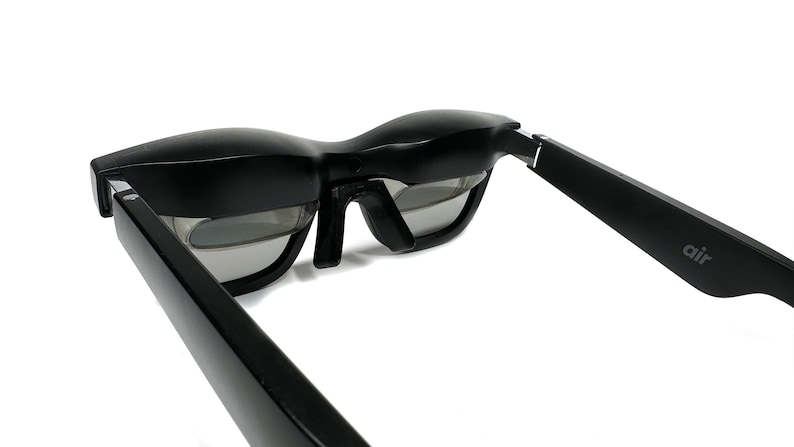 May include: Black framed glasses with a gray lens and the word "air" printed on the side of the frame.