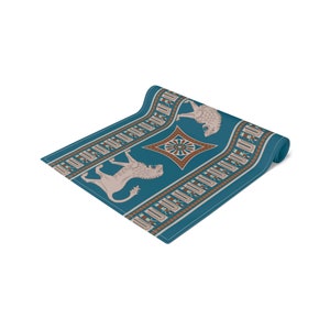 May include: A teal blue yoga mat with a repeating pattern of brown and white geometric shapes and two stylized lions. The mat is rolled up.