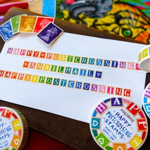 May include: Colorful washi tape rolls with the text "Happy Postcrossing Stamps" and "Snail Mail". The tape is decorated with colorful squares and hearts.