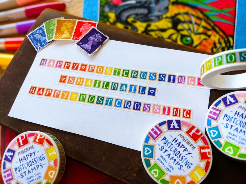 May include: Colorful washi tape rolls with the text "Happy Postcrossing Stamps" and "Snail Mail". The tape is decorated with colorful squares and hearts.
