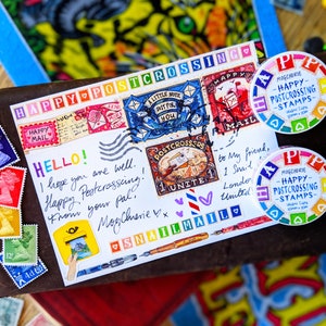 May include: A postcard with a colorful happy postcrossing theme. The postcard has stamps, stickers, and handwritten messages. The postcard is decorated with hearts, a snail, and a message that says "Happy Postcrossing!"