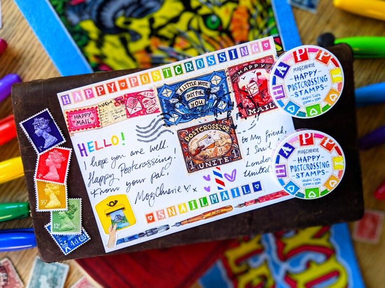 May include: A postcard with a colorful happy postcrossing theme. The postcard has stamps, stickers, and handwritten messages. The postcard is decorated with hearts, a snail, and a message that says "Happy Postcrossing!"