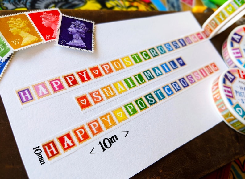 May include: A white card with colorful washi tape featuring the words "Happy Postcrossing", "Snail Mail", and "Happy Postcrossing" with a heart symbol between each word. The tape is 10mm wide and the card also includes the text "< 10m".