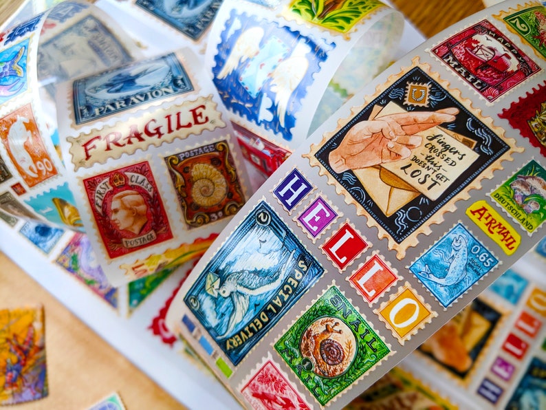 Puede incluir: Un rollo de pegatinas coloridas con patrones y una variedad de dise&ntilde;os, que incluyen un caracol, un pez, un p&aacute;jaro y una mano sosteniendo una carta. Las pegatinas est&aacute;n dispuestas en espiral y tienen un acabado brillante. El texto en las pegatinas dice "HELLO", "SPECIAL DELIVERY", "AIRMAIL", "FINGERS CROSSED" y "POSTAGE".