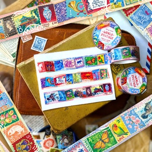 May include: Assortment of colorful washi tapes featuring vintage postage stamps with various designs, including flowers, animals, and buildings. The tapes are rolled up and arranged on a brown leather surface with other decorative items.