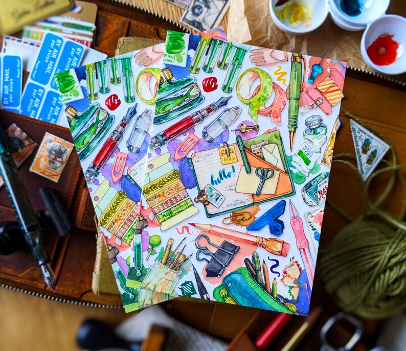 Puede incluir: Una ilustraci&oacute;n de acuarela de una colecci&oacute;n de art&iacute;culos de papeler&iacute;a, que incluyen bol&iacute;grafos, l&aacute;pices, clips y un cuaderno con la palabra "hola" escrita en &eacute;l. La ilustraci&oacute;n est&aacute; en un estilo caprichoso con colores brillantes y una variedad de texturas.