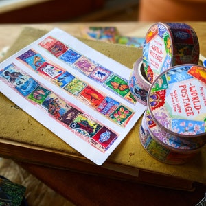 May include: Two rolls of colorful washi tape with a vintage postage stamp design. The tape is labeled "World Postage" and features a variety of stamps from different countries. The tape is 20mm wide and 10 meters long.