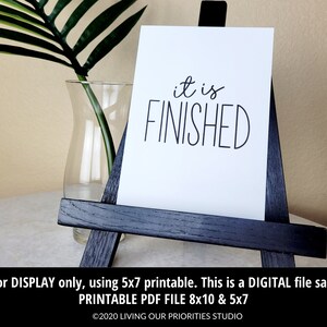 May include: A white printable sign with black text that reads "it is FINISHED". The sign is displayed on a small black easel. The sign is available in 8x10 and 5x7 sizes.