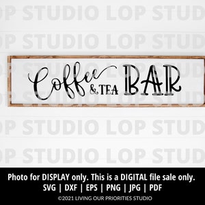 May include: A wooden sign with a brown frame and white background. The sign reads "Coffee & Tea Bar" in black cursive lettering.