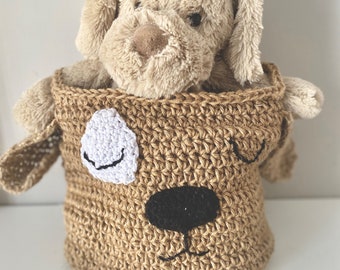May include: A crocheted dog-shaped basket with a brown and white face, holding a plush brown dog toy.