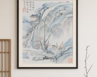 Könnte beinhalten: Gerahmtes, asiatisch inspiriertes Kunstwerk, das eine Berglandschaft mit Wasserfall, Brücke und Figuren auf Pferden darstellt. Das Gemälde weist weiche Blau-, Grün- und Rosatöne auf, mit chinesischen Schriftzeichen in der oberen linken Ecke. Das Kunstwerk hängt über einem Holztisch.