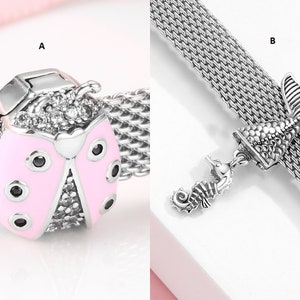 Op de afbeelding: Twee zilveren armbandjes met verschillende bedels. Het eerste armbandje heeft een roze lieveheersbeestje-bedel met zwarte stippen en heldere kristallen. Het tweede armbandje heeft een zilveren bedel van een zeemeerminstaart met een zeepaardje-bedel eraan.
