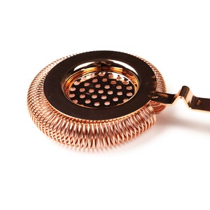 May include: A copper cocktail strainer with a spring-coil design and a handle. The strainer has a fine mesh screen.