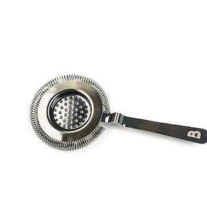 May include: A silver cocktail strainer with a spring coil and a handle with the letter "B" engraved on it.