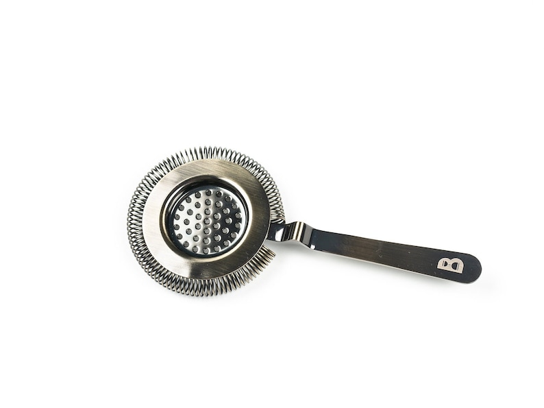May include: A silver cocktail strainer with a spring coil and a handle with the letter "B" engraved on it.