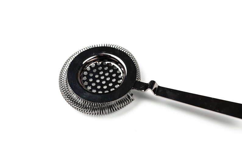 May include: A silver cocktail strainer with a spring-coil design around the edge and a fine mesh screen. The strainer has a long, thin handle.