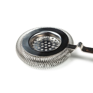 May include: A silver cocktail strainer with a spring-coil design and a handle. The strainer has a round, perforated base.
