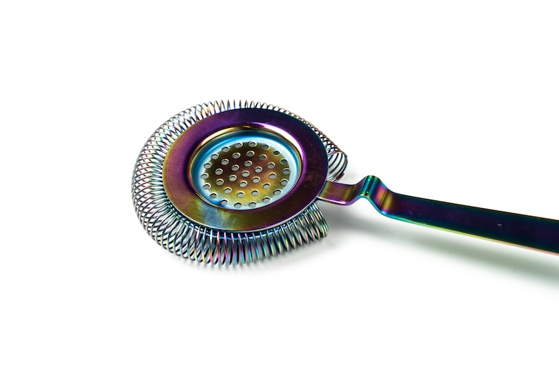 May include: A rainbow-colored cocktail strainer with a spring-coil design and a handle. The strainer is made of metal and has a circular shape with a perforated center.