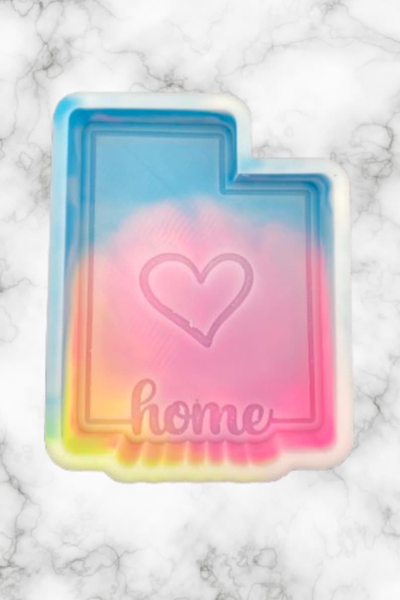 Peut inclure: Un moule en silicone en forme de l'&eacute;tat de l'Utah, aux couleurs de l'arc-en-ciel, avec un c&oelig;ur et le mot "home" &agrave; l'int&eacute;rieur.
