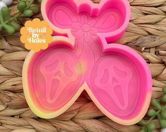 May include: A pink silicone mold featuring two Ghostface masks and a bow design. The mold has a flower detail and the text "Retail by Hales" in a yellow and orange circle.