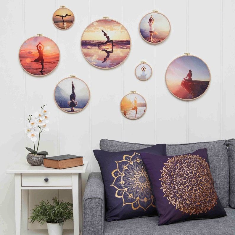 Puede incluir: Una pared blanca con una variedad de fotos redondas enmarcadas de personas haciendo poses de yoga. Las fotos est&aacute;n colgadas en la pared con clips dorados. Hay un sof&aacute; blanco con dos almohadas con dise&ntilde;os de mandala dorados en la parte inferior de la imagen.