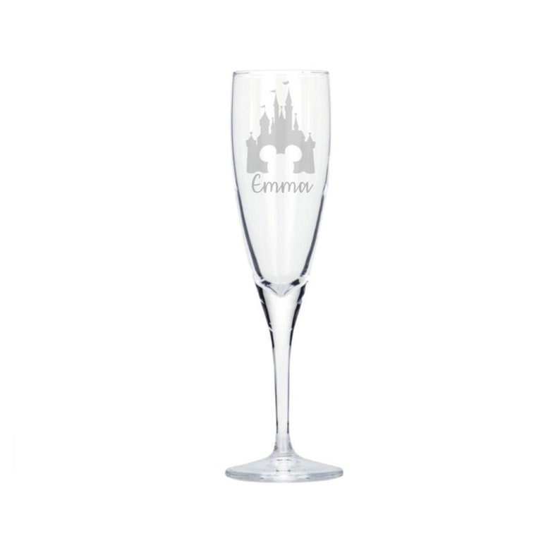 May include: A clear glass champagne flute with an etched design of Cinderella's castle and the text "Emma".