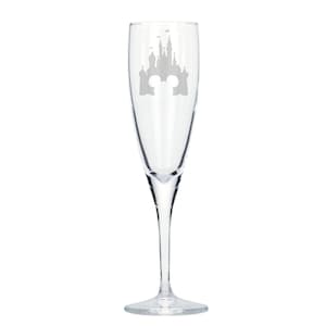 May include: A clear glass champagne flute with an etched design of the Cinderella Castle from Disney World. The castle is outlined in silver and has the iconic Mickey Mouse ears at the top.