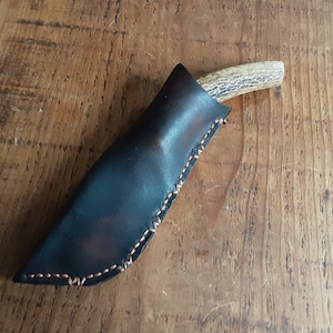May include: A black leather knife sheath with brown stitching and a brown antler handle.