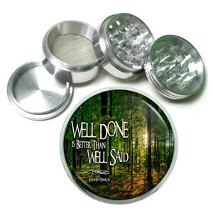 May include: A silver metal grinder with a forest scene on the lid. The lid has the quote "Well done is better than well said - Benjamin Franklin".
