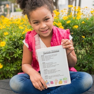 May include: A young girl wearing a pink shirt and blue jeans sits on a wooden bench holding a white sheet of paper with a summer schedule written on it. The schedule includes activities like wake up, breakfast, outdoor playtime, arts and crafts, lunch, educational activity, indoor playtime, snack time, sports or physical activity, free time, dinner, family time or siblings, movie night or family game night, bedtime.