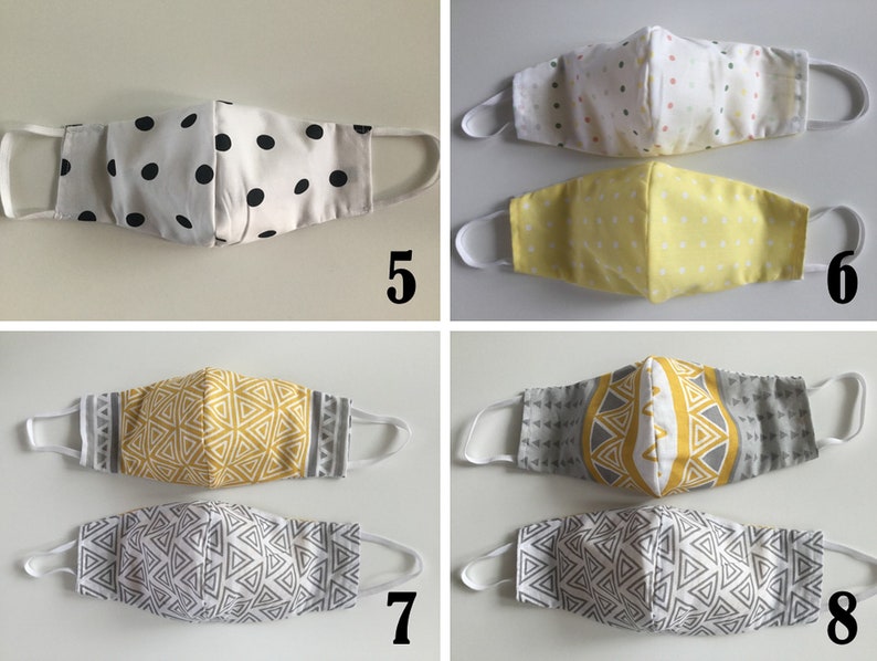 May include: Four different styles of face masks. The first mask is white with black polka dots, the second is yellow with white polka dots, the third is gray with a yellow geometric pattern, and the fourth is white with a gray geometric pattern.