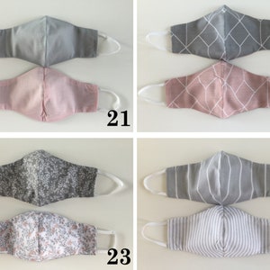 May include: Four pairs of fabric face masks with different patterns. The masks are gray and pink with geometric, floral, and striped patterns. The masks are numbered 21, 22, 23, and 24.