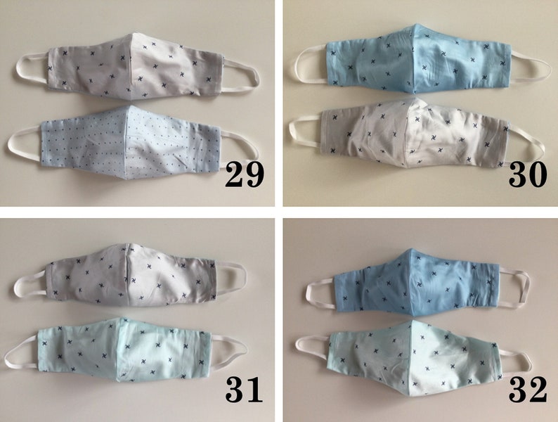 May include: Four pairs of face masks with a white and blue patterned design. The masks are made of fabric and have white elastic ear loops. The masks are numbered 29, 30, 31, and 32.