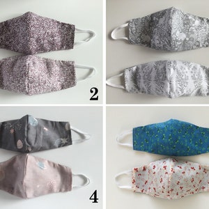 May include: Five pairs of fabric face masks with different patterns. The masks are all white with various colored patterns. The patterns include a gray and white geometric pattern, a gray and white floral pattern, a gray and white space pattern, a blue and white floral pattern, and a red and white floral pattern.