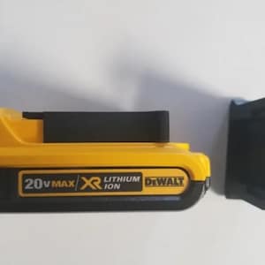 Può includere: Una batteria DEWALT gialla e nera da 20V MAX XR agli ioni di litio con un clip per batteria in plastica nera.