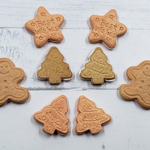 May include: Assortment of gingerbread cookies in various shapes, including gingerbread men, Christmas trees, and stars. The cookies are decorated with icing and have a light brown color.