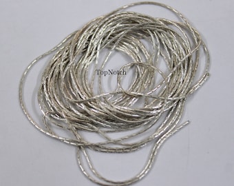 May include: A silver chain with a box chain design. The chain is coiled up and ready to be used for jewelry making.