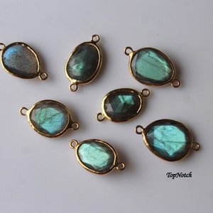 Op de afbeelding: Zeven ovale labradorit edelsteen connectoren met goudkleurige metalen accenten. Elke connector heeft twee lussen om aan sieraden te bevestigen.