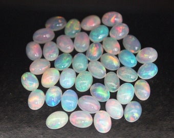 May include: A pile of oval-shaped white opals with iridescent rainbow colors. The opals are smooth and polished.