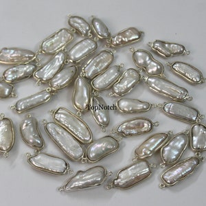 Puede incluir: Una colección de 30 cuentas de perlas barrocas blancas con anillas de salto de plata. Cada perla es única en forma y tamaño, con una forma natural irregular. Las perlas están enhebradas en anillas de salto de plata, lo que las hace listas para ser utilizadas en la elaboración de joyas.