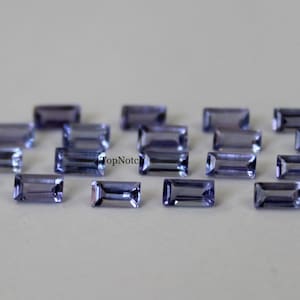 Peut inclure: Une collection de 16 petites pierres précieuses rectangulaires violettes. Les pierres précieuses sont facettées et ont un léger éclat.
