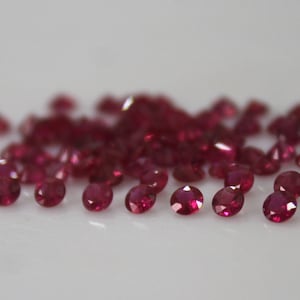 Pode incluir: Um monte de pequenas pedras preciosas de rubi redondas e vermelhas.