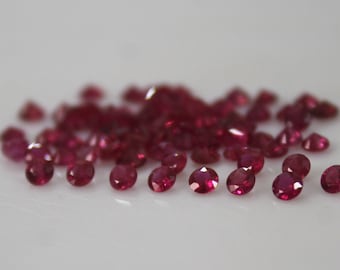 May include: A pile of small, round, red ruby gemstones.